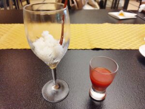 グラスにあまざけのフローズンが入っており、横には小さいグラスに入ったトマトジュースが置かれている