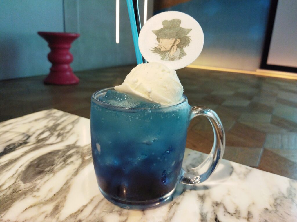 透明なバグカップに入った、青色のクリームソーダの写真