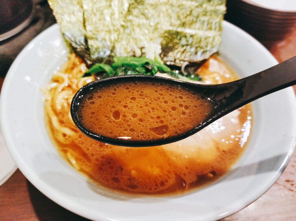 スープを黒のレンゲですくっている写真